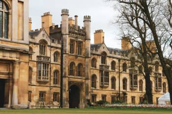 Elegant historic building facade with Gothic architecture and lush garden setting outdoors.